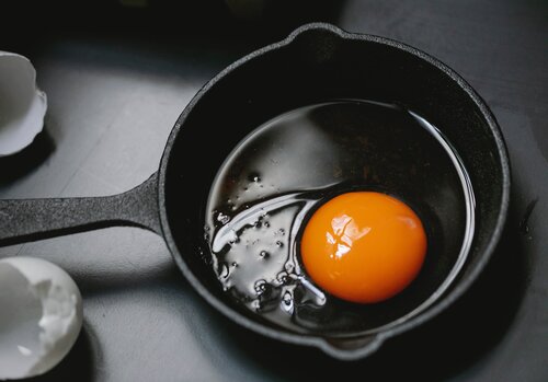 An egg is cracked and sits in a frying pan.