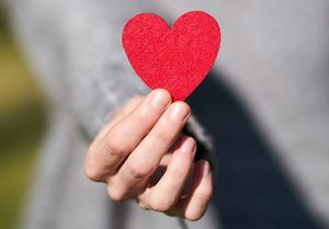 a hand holding a red heart