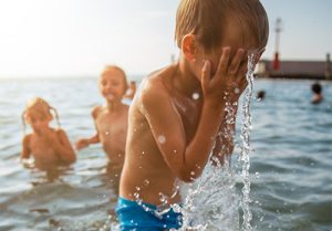 child-splashing-water-on-face-in-lake