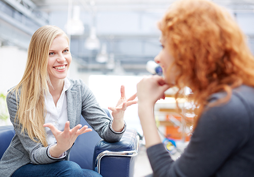 Woman smiling and talking to other woman.