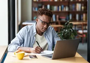 At a cafe, a young man studies with his laptop.