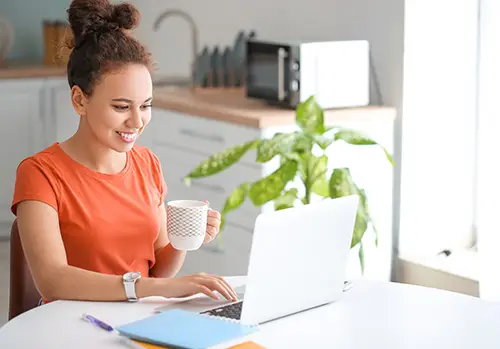 A young woman uses a laptop for online learning at home.
