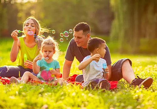 Happy family in the park- family with children blowing soap bubbles outdoors. 